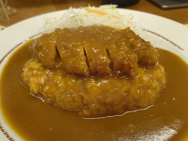 トンカツの上からかけられたカレーは均一にライスを染め皿の線内におさまっている