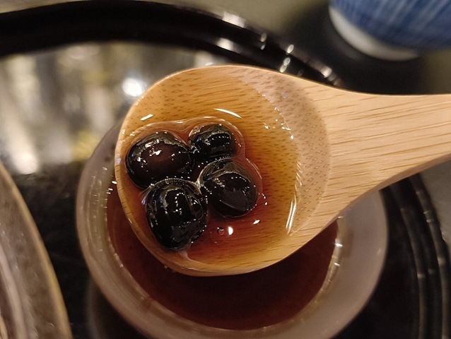 赤えんどう豆を木さじにとり黒蜜をつけてやる