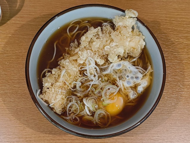 『文殊 浅草店』で「イカ天そば玉落し（いかてんそばぎょくおとし）」でランチ。生たまごを「イカ天」の無い片側に広げれば、イカの「白」と黄身の「黄」が見事なコントラストを描き出す。 その「生たまご」を纏った蕎麦をズルズルと手繰れば、いやはや、もう堪らない。 うまいのだよ（笑）。（文殊 浅草店：浅草一丁目：浅草地下街）