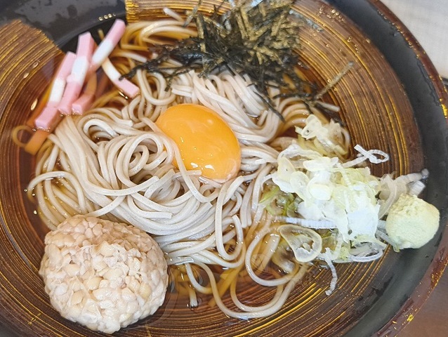 納豆、海苔、そして中央に鎮座する卵黄、そして紅白の蒲鉾の切身が色を添える