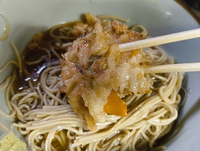 汁の染み込んだかき揚げを食べる