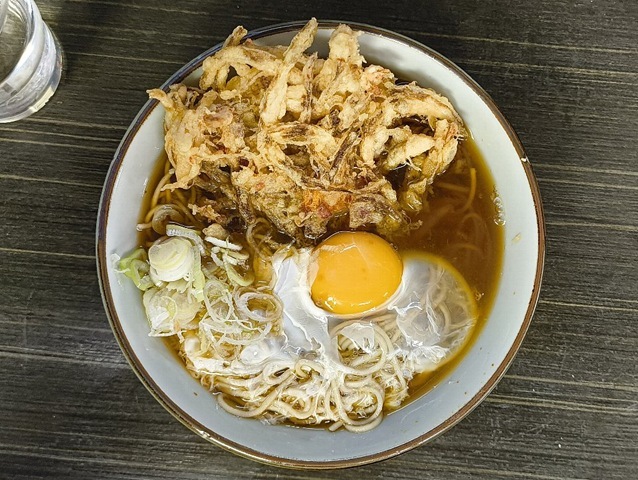 「文殊」の「かき揚げそば」でランチだ。先ずは「かき揚げ」を「汁」に沈め、「汁」を「かき揚げ」に吸わせてやる。 それと同時に油を「蕎麦」に薄く纏わせる。その油を纏った「蕎麦」を手繰ると抜群にうまいのだよ（笑）。（文殊浅草店：浅草一丁目：浅草地下街）