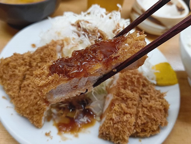 ロースかつにソースをかけて食べる