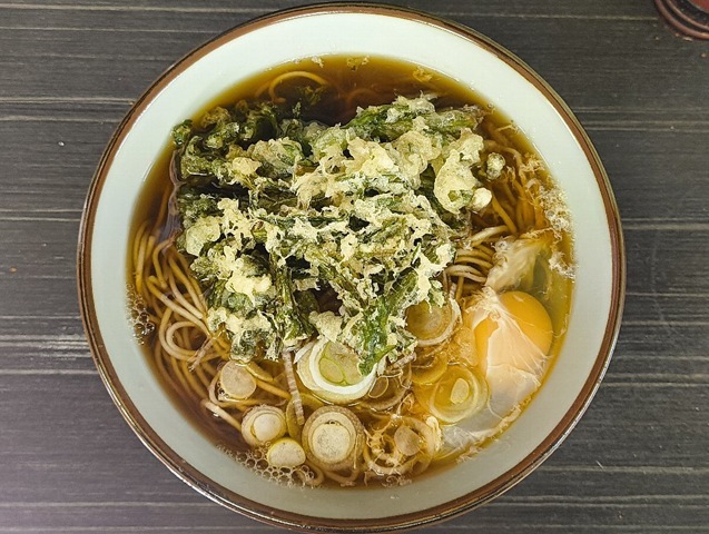 「文殊」の「春菊天そば」＋「生たまご」でランチ。「生たまご」を崩し、「春菊」の緑と「たまご」の黄色の対比を楽しみ、 そして崩した「たまご」を「蕎麦」の絡めて手繰ってやる。これが信じられないぐらいうまいのだよ（笑）。（文殊 浅草店：浅草一丁目：浅草地下街）