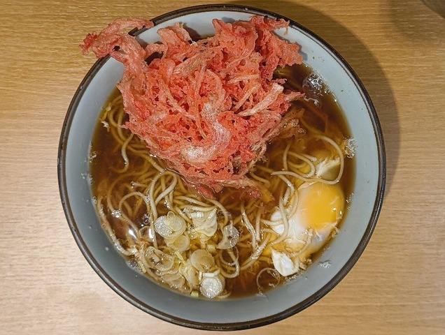『文殊 浅草店』で「紅ショウガ天そば」に「生たまご」を落としてランチ。仕上げに「紅ショウガ天」を食べてやる。 汁を含んでふにゃふにゃになった躯体を箸でそうっと持ち上げ、口へ運ぶ。そりゃあ、うまいのだよ（笑）。（文殊 浅草店：浅草一丁目：浅草地下街）