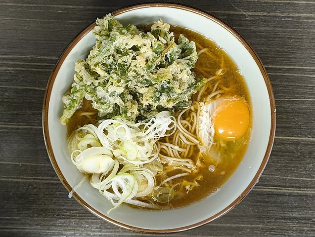 浅草地下街の『文殊』にて「春菊天そば」と「生たまご」のランチ。 赤黒い「汁」に映える緑（春菊天）と黄（たまご）、これぞ無敵のコントラスト。これこそが、浅草地下街における至高のランチだ。今日も、実にうまかったのだよ（笑）。（文殊 浅草店：浅草一丁目：浅草地下街）