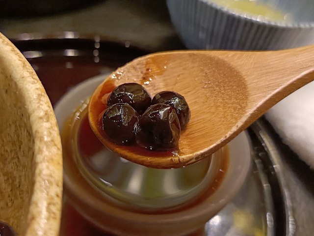 スプーンに豆をのせ、少しだけ黒蜜をのせて食べる