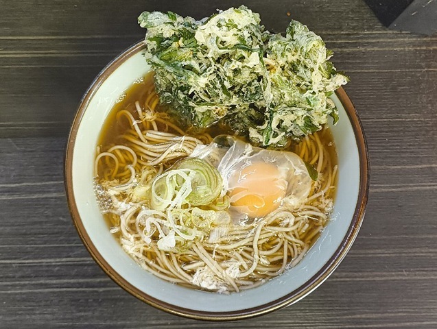 「文殊」の「春菊天そば」と「生たまご」でランチ。今日の「生たまご」の濁り具合は「上」だなと思う。 そしてその上「春菊天」が立っている。 「春菊天」も「上」なのだ。 「汁」の色が赤みがかつた「文殊」色だ。これが立ち喰い蕎麦なのだと云っている。勿論うまかったのだよ（笑）。（文殊 浅草店：浅草一丁目：浅草地下街）