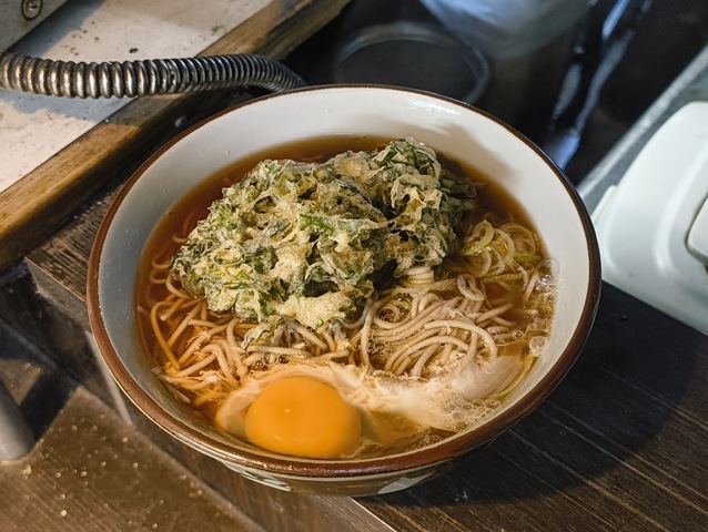 『文殊 浅草店』にて「春菊天そば」と「生たまご」でランチにしたこと。 寒い日の熱い蕎麦。その状況ならば、勿論「春菊天そば」と「生たまご」の選択肢しかなかったのだ。無論、うまかったのだよ（笑）。（文殊 浅草店：浅草一丁目：浅草地下街）